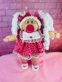 a doll is dressed in pink and white