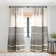 a living room with white walls and black and white striped curtains on the windowsill