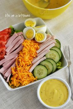 a salad with ham, cheese, cucumbers, and eggs in a bowl