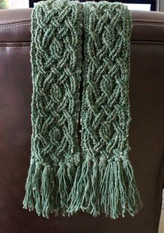 a green knitted scarf sitting on top of a brown chair