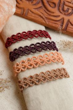 four different colored crochet bracelets sitting on top of a piece of cloth