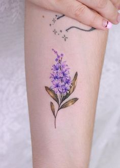 a small purple flower tattoo on the arm