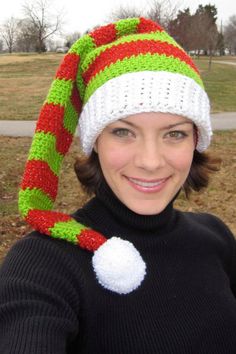 a woman wearing a knitted christmas hat with a candy cane on it's brim