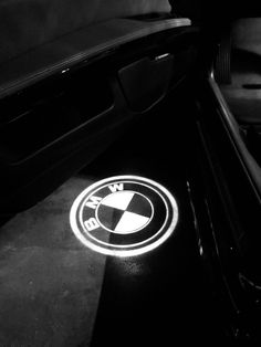 the bmw logo is shown on the floor in this black and white photo, with its door open