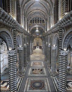 an intricately designed hallway with columns and arches in the center, leading to another room