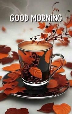 a cup of coffee sitting on top of a saucer with leaves around it and the words good morning