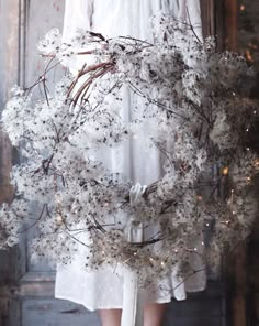 a woman wearing a white dress holding a wreath