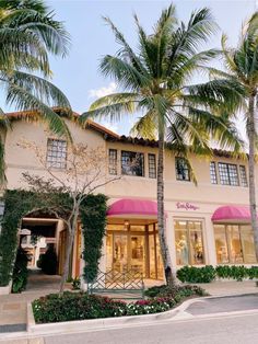 a building with palm trees and pink awnings