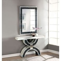 a mirror sitting on top of a table next to a vase with flowers in it