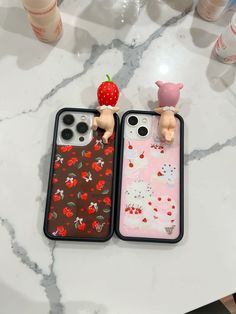 two iphone cases sitting next to each other on a marble counter top with strawberries