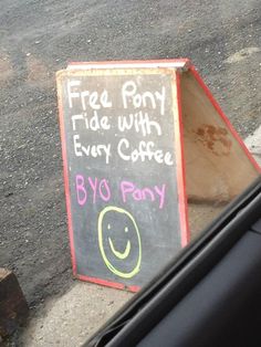 a sign that is sitting on the ground next to a tree stump with a smiley face drawn on it