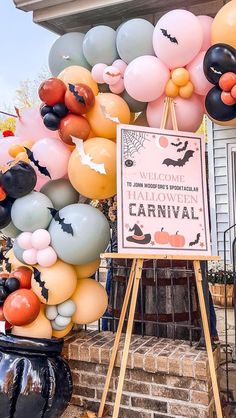 a halloween party with balloons and decorations on the front porch, including a sign that says happy halloween carnival