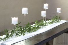 candles and greenery are arranged on a long table