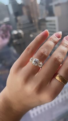 a woman's hand with two rings on it and the other one is wearing a gold band