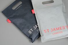 two bags sitting next to each other on top of a gray surface with red lettering