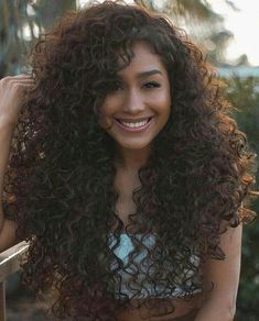 a woman with long curly hair smiling at the camera