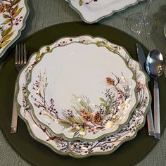 a place setting with plates, silverware and napkins on a green table cloth