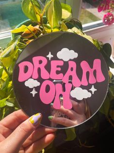 a person holding up a sign that says dream on it in front of some plants