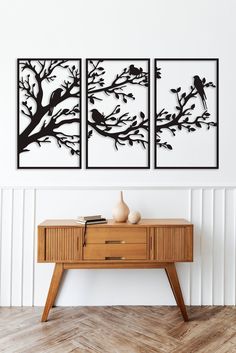 two black and white paintings on the wall above a wooden table