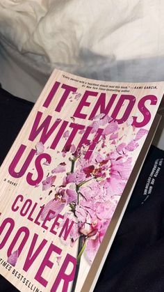 a book sitting on top of a bed next to a white comforter with pink flowers