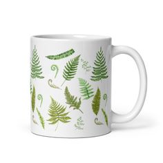 a white coffee mug with green leaves on it