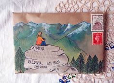 an envelope with a drawing of a man sitting on top of a rock in the mountains