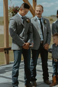 three men standing next to each other holding hands