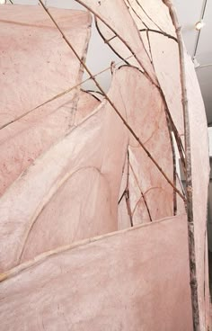 a large pink sculpture with branches sticking out of it's sides and lights hanging from the ceiling