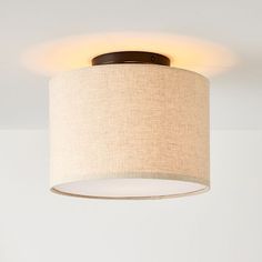 a light that is on in a room with a white wall behind it and a lamp hanging from the ceiling