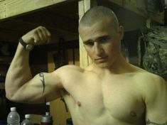 a shirtless man flexing his muscles in a garage