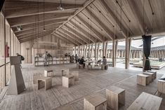 the inside of a building with wooden floors and walls, people are sitting at tables