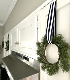 a wreath hanging on the front door of a house with a blue and white striped ribbon