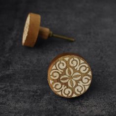 a close up of a wooden button on a black surface with a screw in the middle