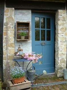 an image of a blue front door with flowers in the window and potted plants outside