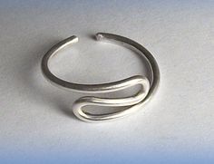 a silver ring sitting on top of a white table next to a light blue background