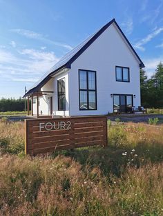 a white house with the word four written on it's side in front of some tall grass