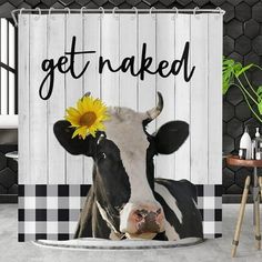 a black and white cow with a sunflower on its head is standing in front of a shower curtain that says get naked