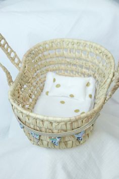 a wicker basket with white and gold polka dots on the bottom, sitting on a white sheet