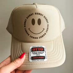 The perfect hat for beach days and country concerts alike! This hat is comprised of an Otto brand foam trucker hat in color khaki with a brown howdy smiley face design. Trendy Beige Trucker Hat, Summer Trucker Hat With Smiley Face, Trendy Beige Trucker Hat, One Size Fits Most, Trendy Brown Trucker Hat For The Beach, Trendy Beige Trucker Hat One Size Fits Most, Trendy Beige Trucker Hat Baseball Cap, Trendy Beige Snapback Trucker Hat, Trendy Brown Trucker Hat With Short Brim, Brown Flat Brim Trucker Hat For Summer