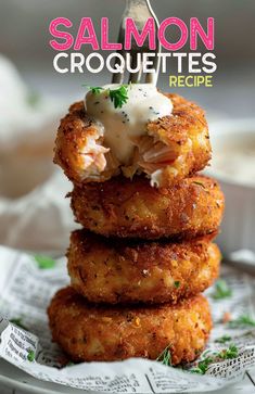 salmon croquettes are stacked on top of each other and topped with sour cream