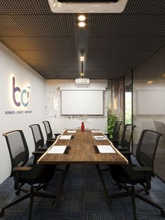 an empty conference room with black chairs and a projector screen on the wall above it