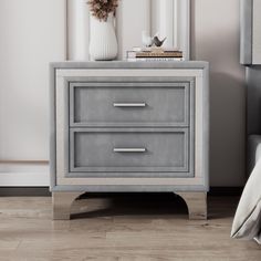 a grey nightstand with two drawers and a white vase sitting on top of it next to a bed