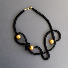 a black leather necklace with gold pearls on it