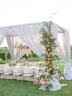 an outdoor wedding setup with white draping and pink flowers