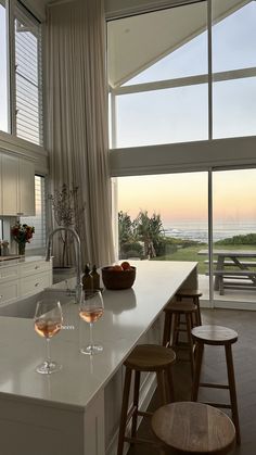 two glasses of wine are sitting on the counter in front of an open kitchen window