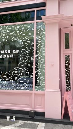 a pink store front with writing on the window