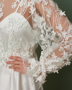 the back of a woman's wedding dress with white flowers and lace on it