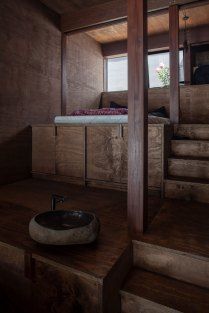 a bowl sitting on top of a wooden table next to some stairs and windows in a room