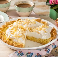 there is a pie on the table with two cups of coffee