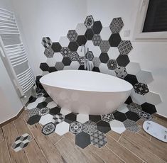 a white bath tub sitting on top of a tiled floor next to a radiator